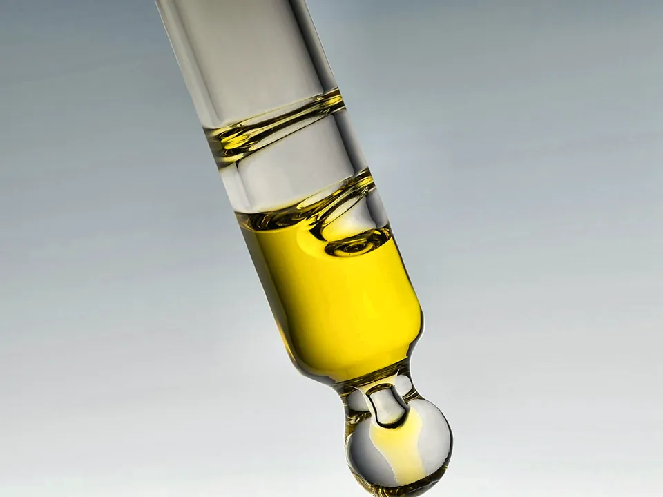 Golden skincare serum dripping from a glass pipette